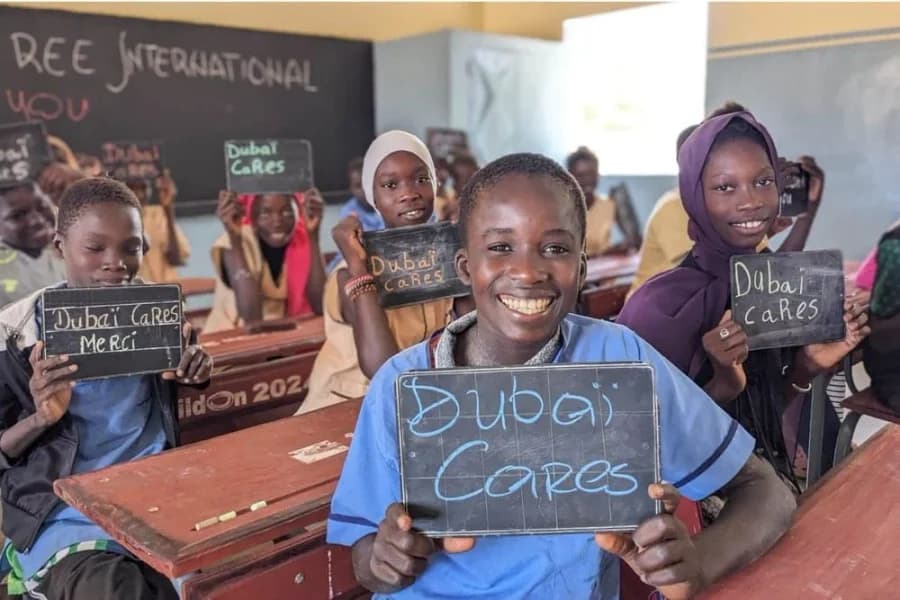 Schoolchildren in a classroom hold up slates that read Dubai Cares